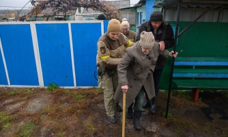 Iäkäs nainen, jota autetaan evakuoitumaan Ukrainassa.