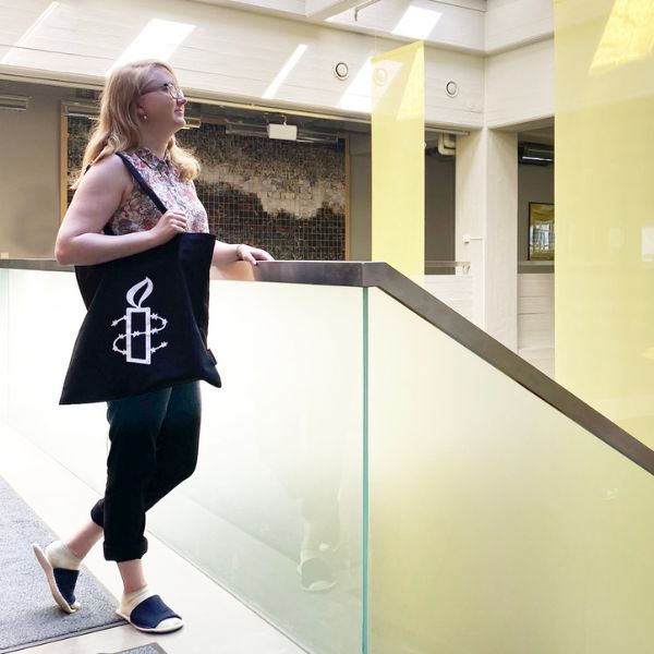 Henkilö pitelee mustaa kangaskassia, jossa on Amnestyn kynttilälogo.