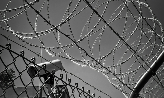 Piikkilanka-aitaa ja valvontakamera.