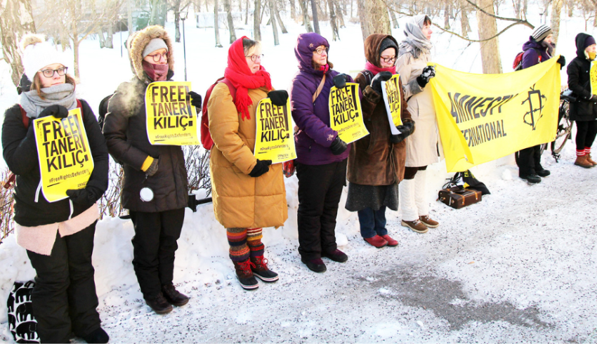 Mielenosoittajia rivissä pitelemässä keltaisia ja mustia julisteita.