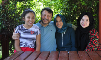 Taner Kılıç hymyilee puolisonsa ja kahden tyttärensä kanssa.