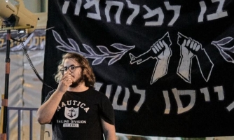 Itamar Greenberg seisoo banderollin edessä.