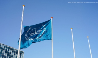 Turkoosi YK-lippu liehuu vasten sinistä taivasta.