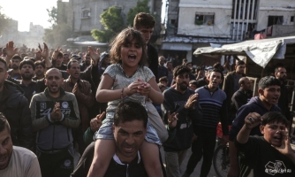 Kuva mielenosoituksesta. Etualalla lapsi istuu aikuisen harteilla väkijoukon keskellä.