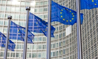 Siniset EU-liput leihuvat saloissa rakennuksen edessä.