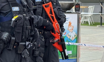 Paineilma-ase FN 303. Poliisi pitää kädessään suurta oranssia asetta.