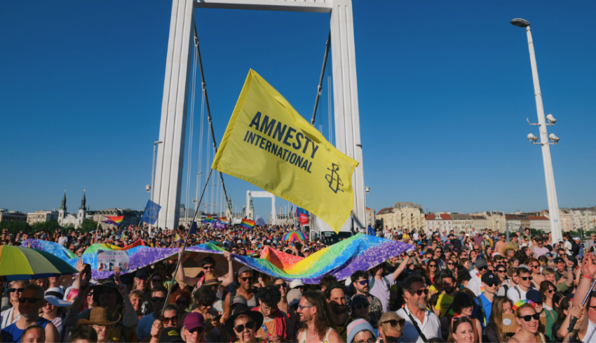 Mielenosoittajia Budapest Prideilla, joukon yllä liehuu keltainen Amnesty-lippu.