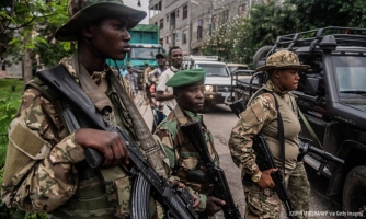 Sotilaita Kongon demokraattisessa tasavallassa. Kolme maastokuvioisiin univormuihin ja kypäriin pukeutunutta henkilöä seisoo rivissä aseet käsissään ja katsoo ohi kameran.